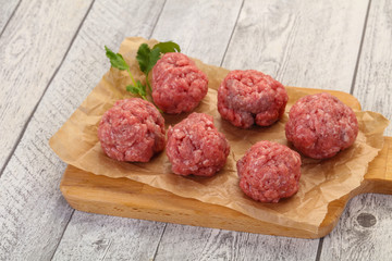Raw meatball over wooden background