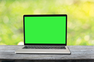 Green screen laptop with sunny abstract green nature background with table, defocused