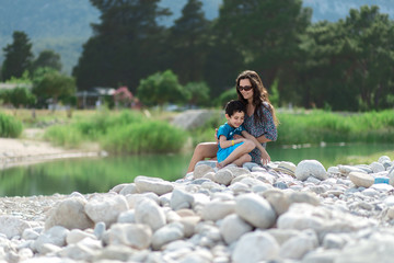 Woman and boy are sitting near the river or lake. Mother and son. Mother's day. Family 