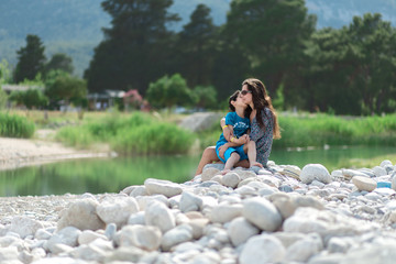 Woman and boy are sitting near the river or lake. Mother and son. Mother's day. Family