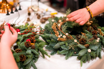 Christmas wreath weaving workshop. Woman hands decorating holida