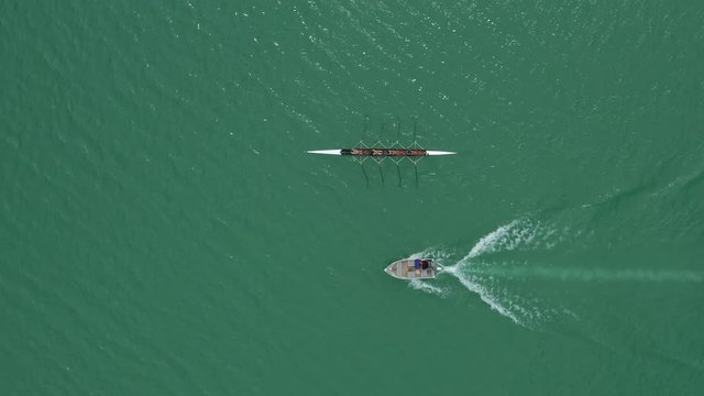 Aerial close to high shot over a rowing team with a coach on a boat lake Saint Cassien watersport France reservoir var