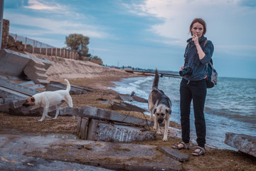 Woman with dogs on the ruins of destroyed buildings on the beach. Destruction from the storm.