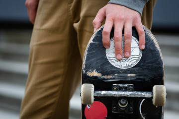 Skater hand holding skateboard deck in an urban suroundings outd
