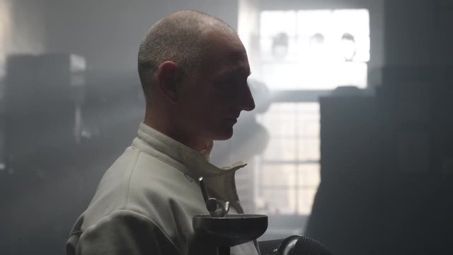 Pan Across An Older Man Silhouetted By Bright Window In A Dark And Foggy Locker Room