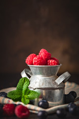 Raspberries and blueberries in a Cup on a dark background. Summer and healthy food concept....