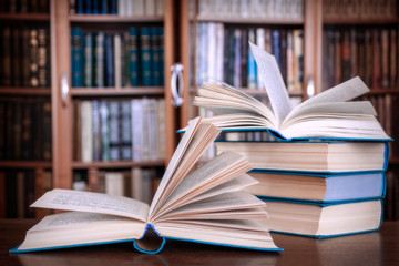 Books lie on the table against the background of bookcases.