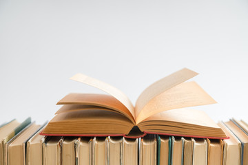 Open book on white background, hardback books on wooden table. E