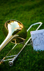 A trombone lies on the grass before an open air concert