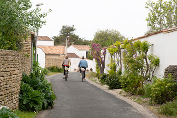 mother and daughter come back from the market of the Ile de Ré by bike in the alley in France
