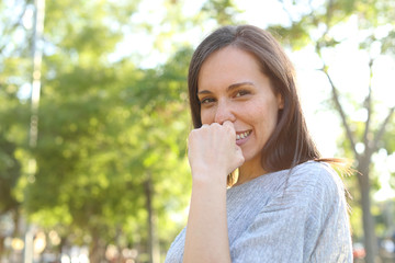 Timid adult woman posing looking at you in a park