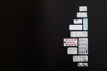 Packaging of tablets and pills on black background. Drug prescri