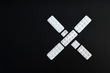 X shape made of packaging of tablets and pills on black backgrou