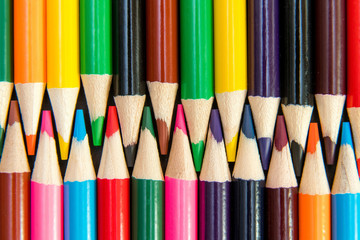 Fototapeta premium Close-up of colored pencils arranged in interlock pattern on whi