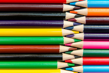 Close-up of colored pencils arranged in interlock pattern on whi