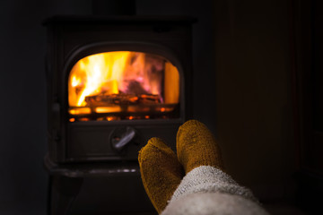 Feet in woollen socks by the Christmas fireplace. Woman or man r