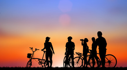 Obraz premium Silhouette group friend and bike relaxing on blurry sunset background.