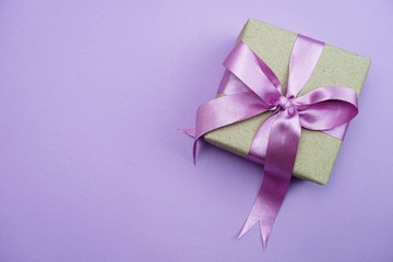 Gift box with pink bow ribbon on purple background