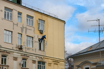 Fototapeta na wymiar MOSCOW - OCTOBER 27, 2018: A working painter - a mountaineer is painting a residential building