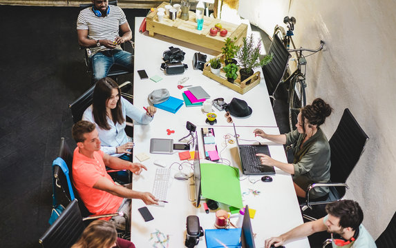Young co-workers team talking during startup - Happy people planning a new project in creative workplace office - Technology, entrepreneur, marketing and concept - Focus on black man with headphones