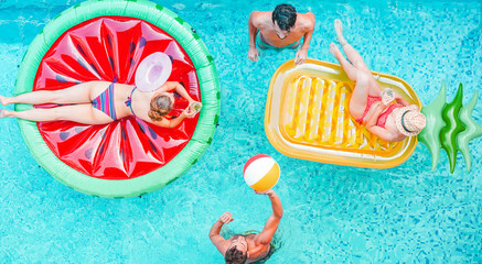 Happy friends playing with air lilo ball inside swimming pool - Young people having fun on summer...
