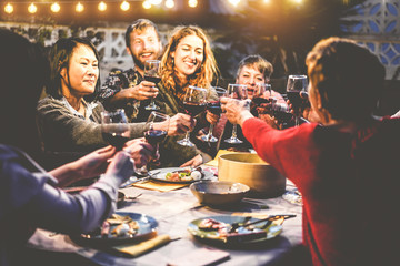 Happy family eating and drinking wine at barbecue dinner outdoor - Multiracial mature and young people having fun at bbq sunday meal - Food and summer lifestyle concept - Focus on asian woman face