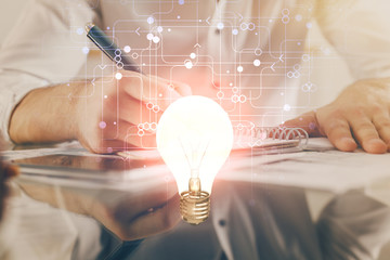 View of Bulb lamp idea concept icon on a futuristic interface with writing man's hand background....