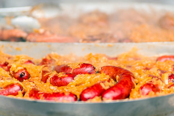 Spicy red pork meat sausages with golden cabbage cooking on hot