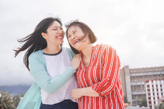 Asian mother and daughter having fun outdoor - Happy family people enjoying time togehter around city in Asia - Love, parenthood lifestyle, tender moments concept - Focus on faces