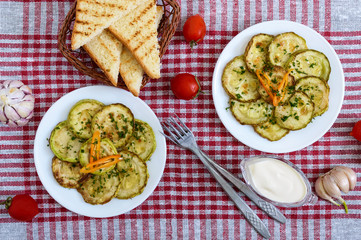 Tasty fried zucchini slices on a plate with sauce on a wooden table. Picnic snack. Rustic style. Top view, flat lay.