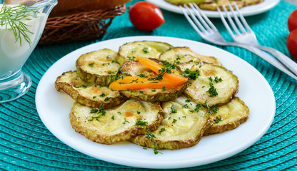 Tasty fried zucchini slices on a plate with sauce on a wooden table. Picnic snack. Rustic style