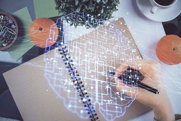 Double exposure of writing hand on background with brain hologram. Concept of learning.