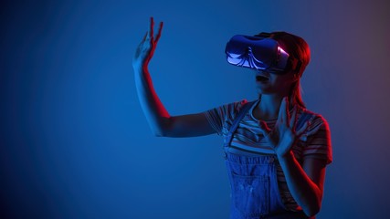 The game vr.The girl in the helmet and with the controller plays a game with creative light.