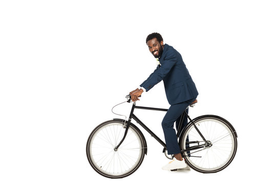 happy african american bridegroom riding bicycle isolated on white