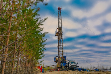 Drilling a deep well mobile drilling rig in an oil and gas field. The field is located in the Far North in the taiga. Beautiful dramatic sunset sky in the background.