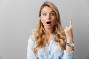 Pretty blonde business woman posing isolated shocked excited grey wall background.