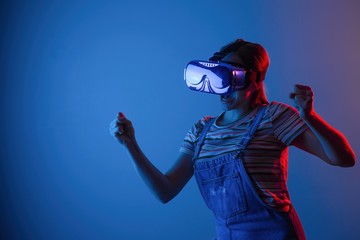The game vr.The girl in the helmet and with the controller plays a game with creative light.