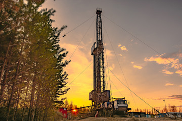 Drilling a deep well mobile drilling rig in an oil and gas field. The field is located in the Far North in the taiga. Beautiful dramatic sunset sky in the background.