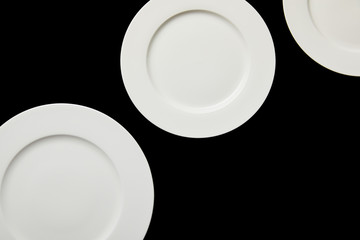 top view of white empty round plates isolated on black