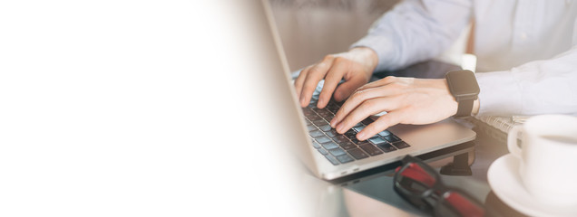 Cropped image of a young man working on his laptop, man hands busy using laptop at office desk....
