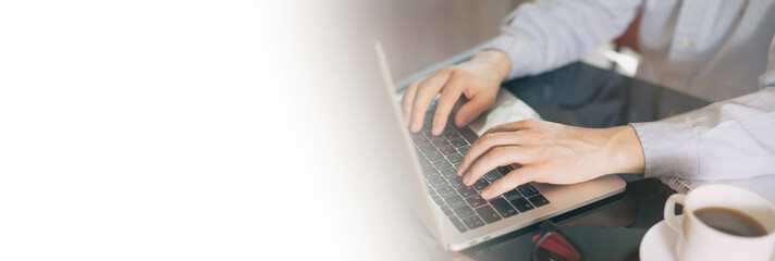 Cropped image of a young man working on his laptop, man hands busy using laptop at office desk....