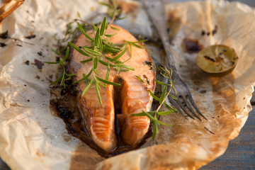 Grilled red salmon steak served with lime and glass water, newspaper  on white plate. Sockeye salmon