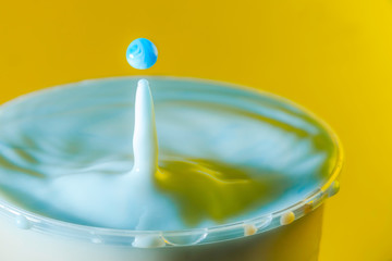 high speed photograph of a milk drop on yellow background in the