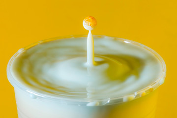 high speed photograph of a milk drop on yellow background in the