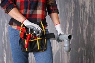 Plumber with tools belt on grunge background, closeup