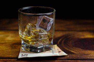 Left A Tip in the bar for the drink. Euro dollar bill and glass of whiskey on wooden table. Payment for alcohol