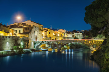 Fototapeta na wymiar Medieval stone bridge and Mercatale Gate (Porta Mercatale) at dusk in Prato, Tuscany, Italy