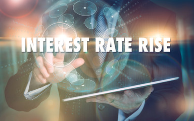 A hand selecting a Interest Rate Rise business concept on a futuristic computer display.