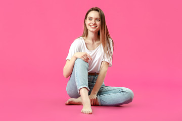 Stylish young woman in jeans on color background