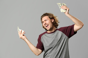 Happy man with money on grey background